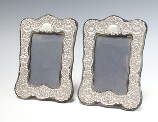 A pair of Victorian style repousse silver rectangular photograph frames decorated with scrolls and birds, London 1987, 21cm x 14cm 