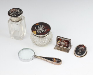 A silver and tortoiseshell plique a jour cut glass toilet jar, a tall ditto, a mounted magnifying glass, a menu holder and letter clip, London 1908, 1910, 1914 