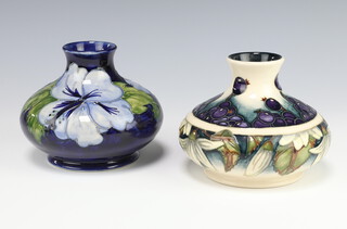 A modern Moorcroft squat baluster vase decorated the Juneberry pattern by Anji Davenport, impressed marks dated 2000, 10cm, a ditto dark blue vase decorated hibiscus pattern, impressed marks 10cm 