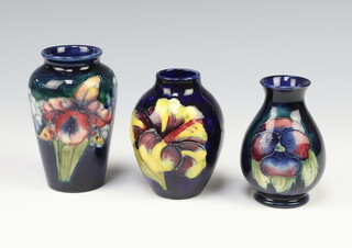A Moorcroft blue ground baluster vase decorated pansies 9cm, ditto orchid pattern 10cm and another decorated Hibiscus 9cm 