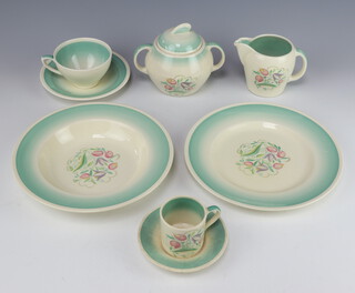 A Susie Cooper Art Deco tea, coffee and dinner service decorated with stylised flowers comprising 6 coffee cans, 8 saucers (2 cracked), 7 tea cups, 10 saucers, milk jug, sugar bowl and cover, cheese dish and cover, sauce boat (cracked), egg cup stand, 2 small dishes, 2 small bowls (1 cracked), 5 dinner plates (1 cracked), 7 medium plates, 6 side plates, cake plate and 2 small plates, 6 soup bowls (2 chipped)