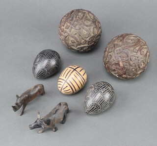 Two curious turned and carved hardwood boulles 8cm, 3 carved hardstone model eggs 6cm, a hardwood figure of a buffalo and a rhinoceros 5cm   