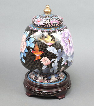A 20th Century Chinese black ground cloisonne enamelled urn and cover decorated birds amongst flowers, raised on a hardwood stand 28cm x 15cm 
