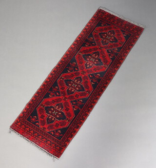 A black and red ground Afghan runner with 4 stylised medallions to the centre 143cm x 50cm 