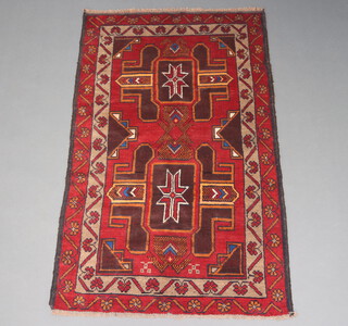 A tan and red ground Belouche rug with 2 stylised medallions to the centre 150cm x 92cm