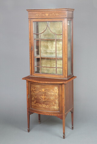 An Edwardian inlaid mahogany display cabinet on cabinet, the upper section fitted shelves enclosed by astragal glazed doors, the crossbanded bow front base enclosed by a panelled door, raised on square tapered supports, spade feet 180cm h x 69cm w x 46cm d 