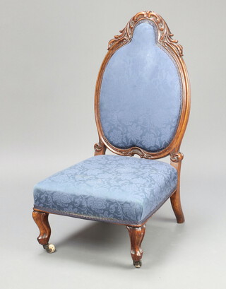 A Victorian carved mahogany show frame nursing chair upholstered in blue material, raised on cabriole supports 79cm h x 46cm w x 47cm d 