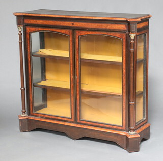 A Victorian ebonised and amboyna display cabinet, fitted shelves enclosed by a pair of arch panelled doors with turned and fluted columns to the sides with gilt metal mounts 106cm h x 119cm w x 38cm d 