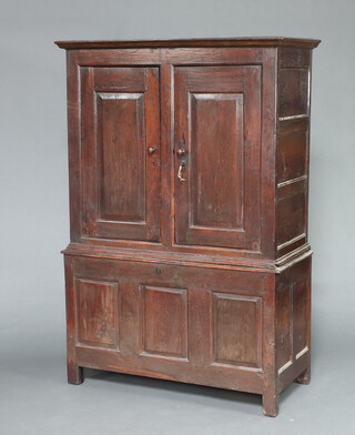 An oak press cabinet formed from old timber, the upper section with moulded cornice enclosed by pair of panelled doors, the base formed from a coffer 172cm h x 116cm w x 50cm d 