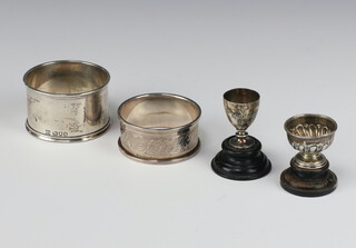 An Edwardian silver miniature pedestal rose bowl, Chester 1908, 2cm on a wooden socle, a ditto cup Birmingham 1906 2.5cm on a wood socle, together with 2 napkin rings