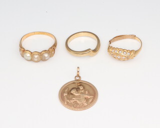 Three yellow metal gem set rings, unmarked, all size N and a 9ct yellow gold St Christopher medallion, gross weight 11.3 grams 