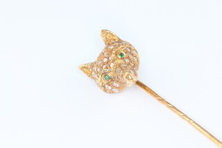 A yellow metal tie pin in the form of a foxes head set with diamonds and emeralds 