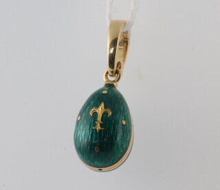 Faberge, a yellow metal 750 green guilloche enamel egg pendant decorated with a fleur de lis, numbered 492 of 500, 3.9 grams, 25mm from the top of loop, boxed and with certificate