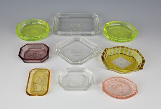 Eight Baccarat coloured glass pin trays - 2 oval green depicting a girl blowing bubbles and Dutch boy smokers 9cm, a clear glass pin tray decorated with Dutch boy smokers 12.5cm, an octagonal ditto decorated with a Pekinese 9.5cm, another decorated a galleon 7cm, an orange glass ditto decorated classical figures 6.5cm, an octagonal purple ditto decorated with classical figures 7cm and a pink ditto decorated with a cat 7cm, together with a similar 2 colour ditto with monogram 9cm 