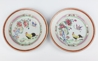 A pair of Chinese export famille rose plates, Qing dynasty, Qianlong period each painted with a cockerel and butterfly in a garden amongst peony and rockwork, 22.5cm diam