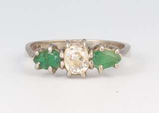 An 18ct white gold diamond and emerald ring, the mine cut diamond approx. 0.5ct, the pear cut emeralds each approx. 0.25ct, 2.8 grams, size L 