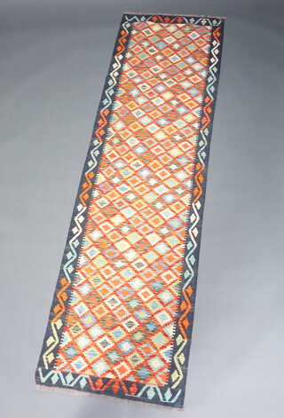 A yellow, green and orange ground Chobi Kilim runner with all over geometric design 295cm x 84cm 