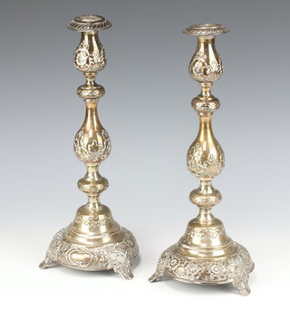 A pair of Continental white metal repousse waisted candlesticks decorated with flowers and fruits bearing import marks London 1917, 773 grams, 34cm 