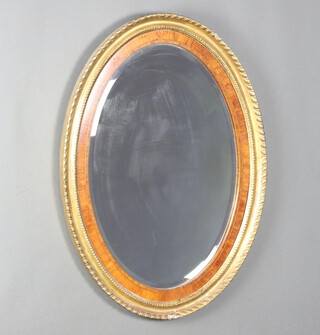 A 19th Century style oval bevelled plate wall mirror contained in a gilt and walnut finished frame 82cm h x 90cm w 