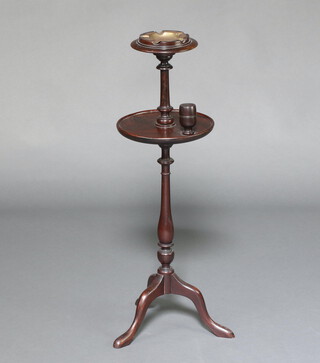 A 1930's turned mahogany 2 tier smoker's stand, the top fitted a brass ashtray, the lower section a match striker, raised on a turned column and tripod base 83cm h x 26cm diam. 