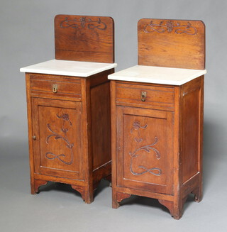 A pair of Continental Art Nouveau carved oak and white veined marble bedside cabinets with raised backs, fitted a drawer above cupboard enclosed by a panelled door 108cm h x 46cm w x 37cm d 