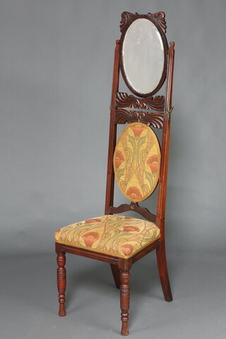 An Edwardian Art Nouveau metamorphic carved mahogany show frame chair, the rising back fitted a bevelled oval plate mirror, upholstered in floral material on turned supports 102cm h x 46cm w x 41cm d 