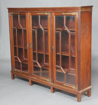 An Art Nouveau mahogany library triple bookcase with moulded cornice, fitted adjustable shelves enclosed by 3 astragal glazed panelled doors, raised on square reeded supports 149cm h x 180cm w x 31cm d  