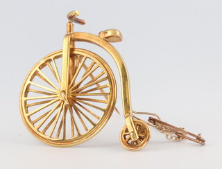 A yellow metal penny farthing brooch by Paul Eaton, 12.9 grams 