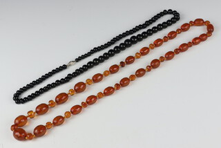 An amberoid facetted necklace 74cm and one other necklace 64cm