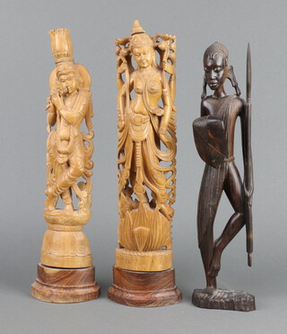 A pair of Thai carved and pierced wooden figures of standing ladies 42cm h, together with a carved figure of a tribes woman with shield and spear 40cm h  