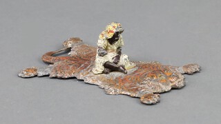 A 1930's cold painted metal paperweight in the form of a gentleman seated on a lion skin rug 3cm x 12cm x 8cm 