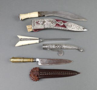 A Kukri with 18cm blade complete with 2 skinning knives with horn grips and an embossed metal and plush scabbard, a dagger with 9cm blade, horn grip and an embossed metal scabbard together with a dagger with 11cm blade, gilt metal grip and leather scabbard (blade rusted)  