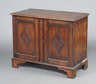 A carved oak cabinet formed from old timber, the top formed from 4 planks, raised on bracket feet enclosed by panelled doors 78cm h x 99cm w x 50cm 