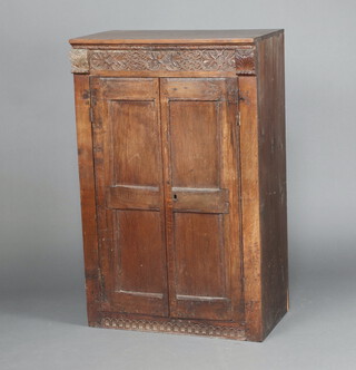 An 18th/19th Century carved oak cabinet constructed of 18th Century and later timber, the interior fitted shelves enclosed by a panelled door 108cm h x 74cm w x 43cm d  