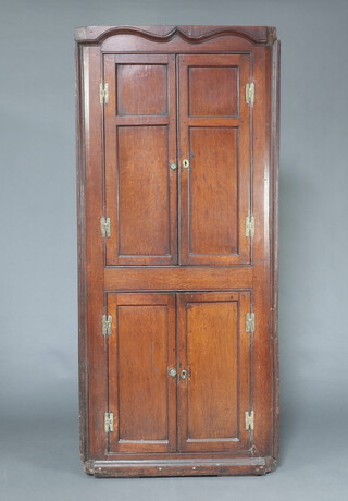 An 18th Century oak double corner cabinet with moulded cornice, both sections enclosed by panelled doors with H framed brass hinges 201cm h x 90cm w x 64cm d 