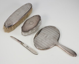 A silver engine turned hand mirror with engraved monogram Birmingham 1928, minor dents, together with a silver mother of pearl fruit knife, hair brush and trinket box 