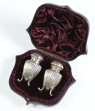 A pair of Victorian repousse fluted peppers on scroll feet, Birmingham 1886, 6cm, 43 grams, contained in original fitted case 