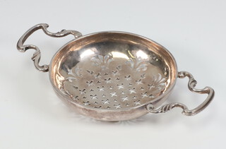 A Georgian silver pierced lemon strainer with scroll handles, 71 grams, 15cm, (hallmarks rubbed)