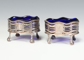 A pair of George III silver oval salts with pierced and armorial decoration on claw and ball feet, having blue glass liners, London 1777, 89 grams 