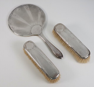 A 3 piece silver dressing table set comprising hand mirror and 2 clothes brushes, Birmingham 1913 