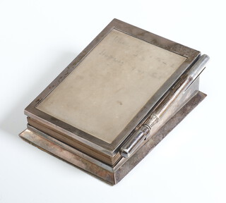 A George V silver desk top aide memoire of sloping form with original fitted notepaper and propelling pencil, London 1911, maker Asprey & Co, 11cm 