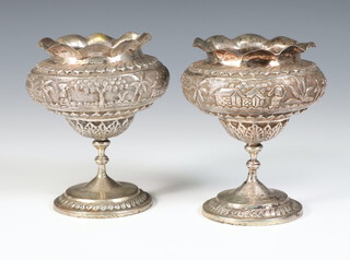 A pair of Indian white metal waisted baluster vases decorated with figures, flowers and animals 11cm