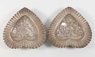 A pair of Indian white metal repousse heart shaped dishes decorated with lions and elephants, building and trees, 13cm, 172 grams 