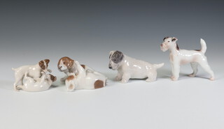 A Bing and Grondahl figure of a standing Wire haired Terrier 2072 9cm, a Danish Terrier puppy 1452/3086 10cm, a Royal Copenhagen group of 2 puppies playing 1453/2270 7cm and 2 ditto Spaniel Puppies playing 1453/453 9cm 