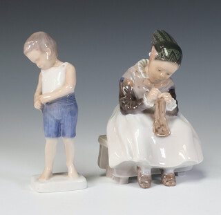 A Royal Copenhagen figure of a seated girl knitting 1314 15cm, a Bing and Grondahl figure of a boy 1759 15cm 
