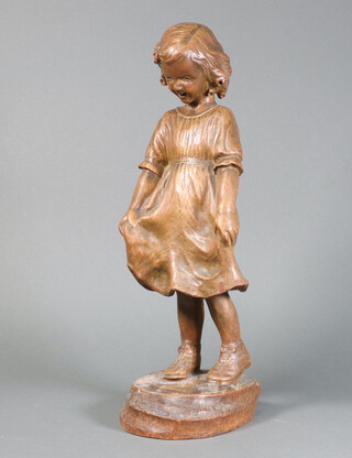 A 1930's carved figure of a standing girl raised on an oval base 44cm h 
