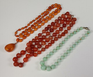 An amber graduated oval bead necklace 86cm, an agate ditto 44cm and a green hardstone bead necklace 40cm  