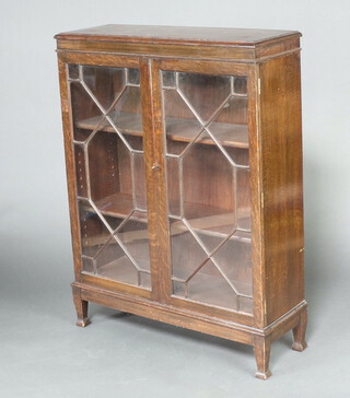 A 1930's oak display cabinet fitted shelves enclosed by astragal glazed panelled doors 123cm h x 91cm w x 31cm d 