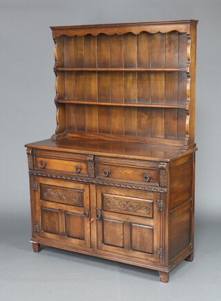 A carved oak dresser, the raised back fitted shelves, the base fitted 2 drawers above cupboard enclosed by panelled doors 175cm h x 123cm w x 47cm d 