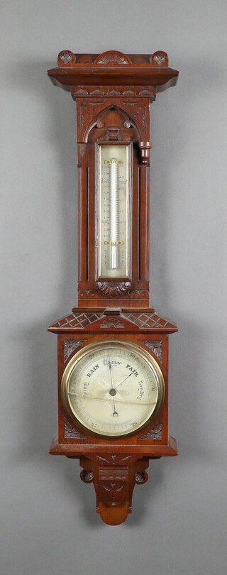 An Edwardian aneroid barometer and thermometer with silvered dial, contained in a carved walnut case 26cm x 8cm (glass cracked)